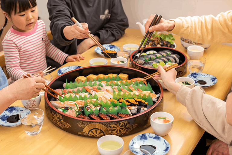 回転寿司すし丸をテイクアウトし、お家で食事を楽しむ家族